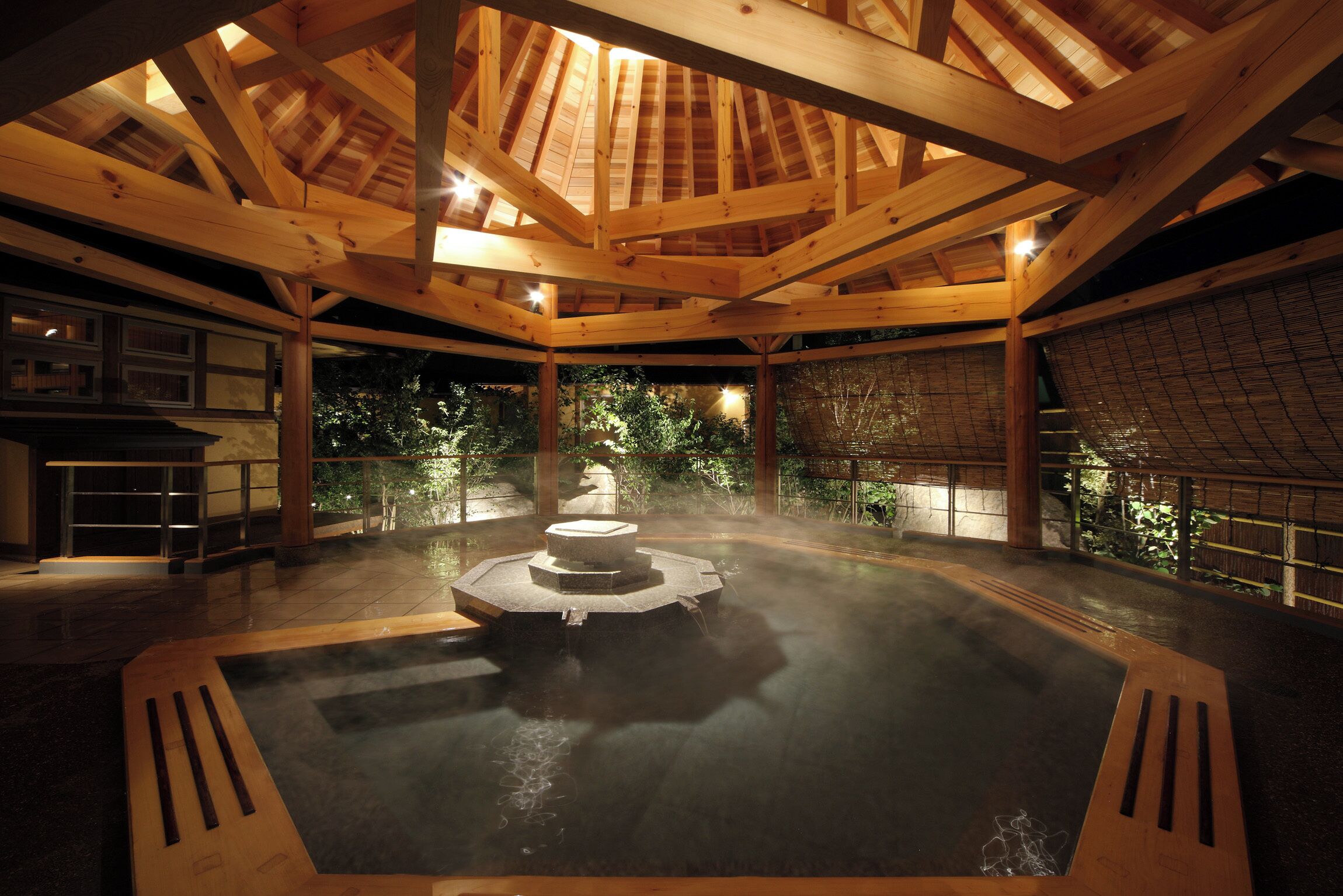 A traditional Japanese hot spring bath with wooden beams and a stone fountain.