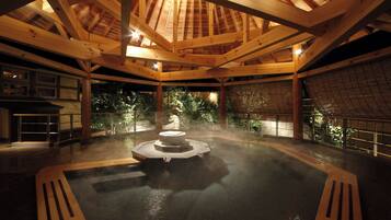 A traditional Japanese hot spring bath with wooden beams and a stone fountain.