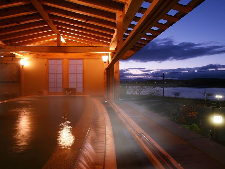 A wooden deck with a view of a lake at dusk.
