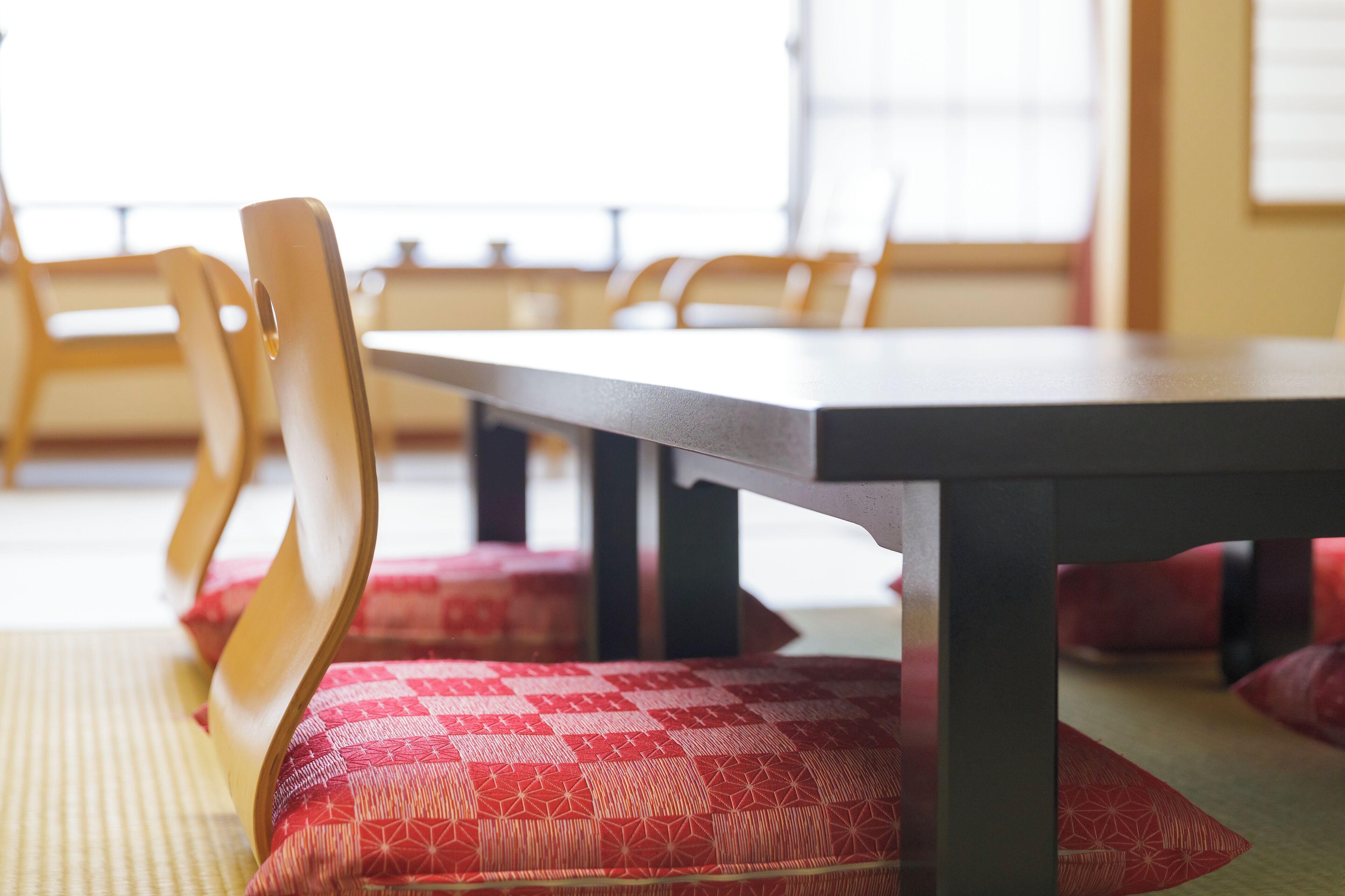 A dining area with wooden chairs and red patterned cushions.