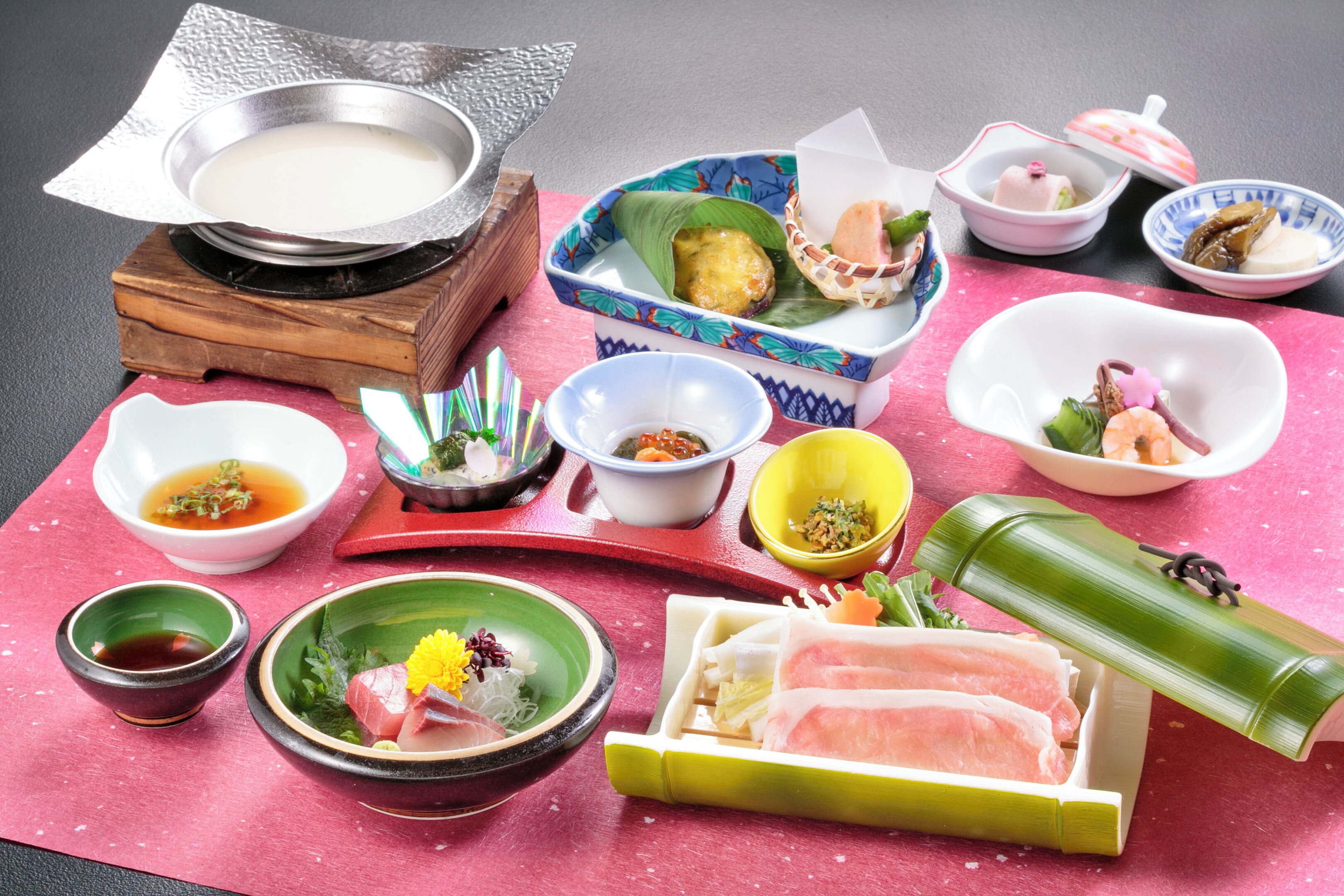 A variety of traditional Japanese dishes arranged on a table with a pink tablecloth.