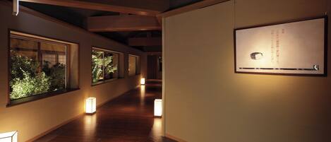 Un pasillo con suelo de madera, iluminación empotrada y ventanas que dan a vistas de follaje.