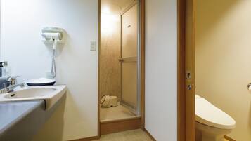 A bathroom with a sink, toilet, and a shower area.
