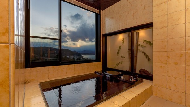 A modern bathroom with a large window, a bathtub, and a decorative bamboo wall. - Hotel Shion (Morioka)