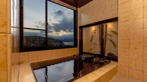 Un baño moderno con un ventanal grande, una bañera y un llamativo revestimiento de bambú.