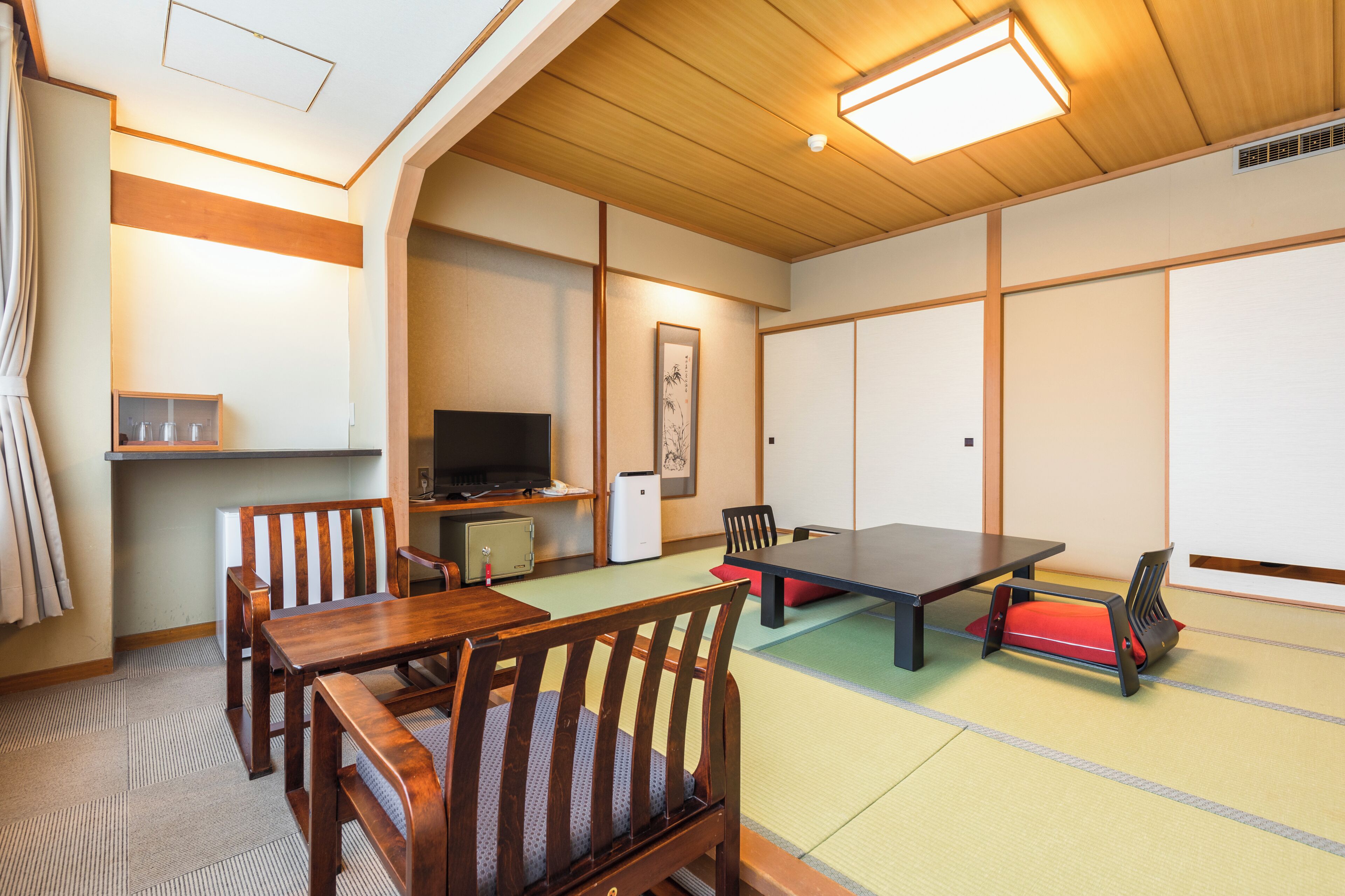 A traditional Japanese room with tatami flooring, a low table, and wooden furniture.