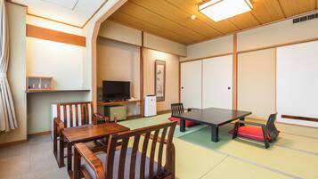 A traditional Japanese room with tatami flooring, a low table, and wooden furniture.