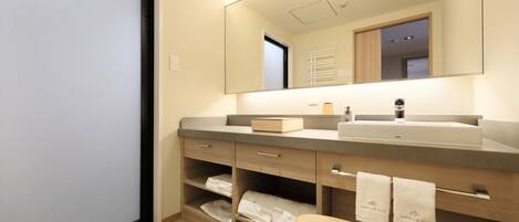 A modern bathroom with a large mirror, a sink, and a vanity with shelves.