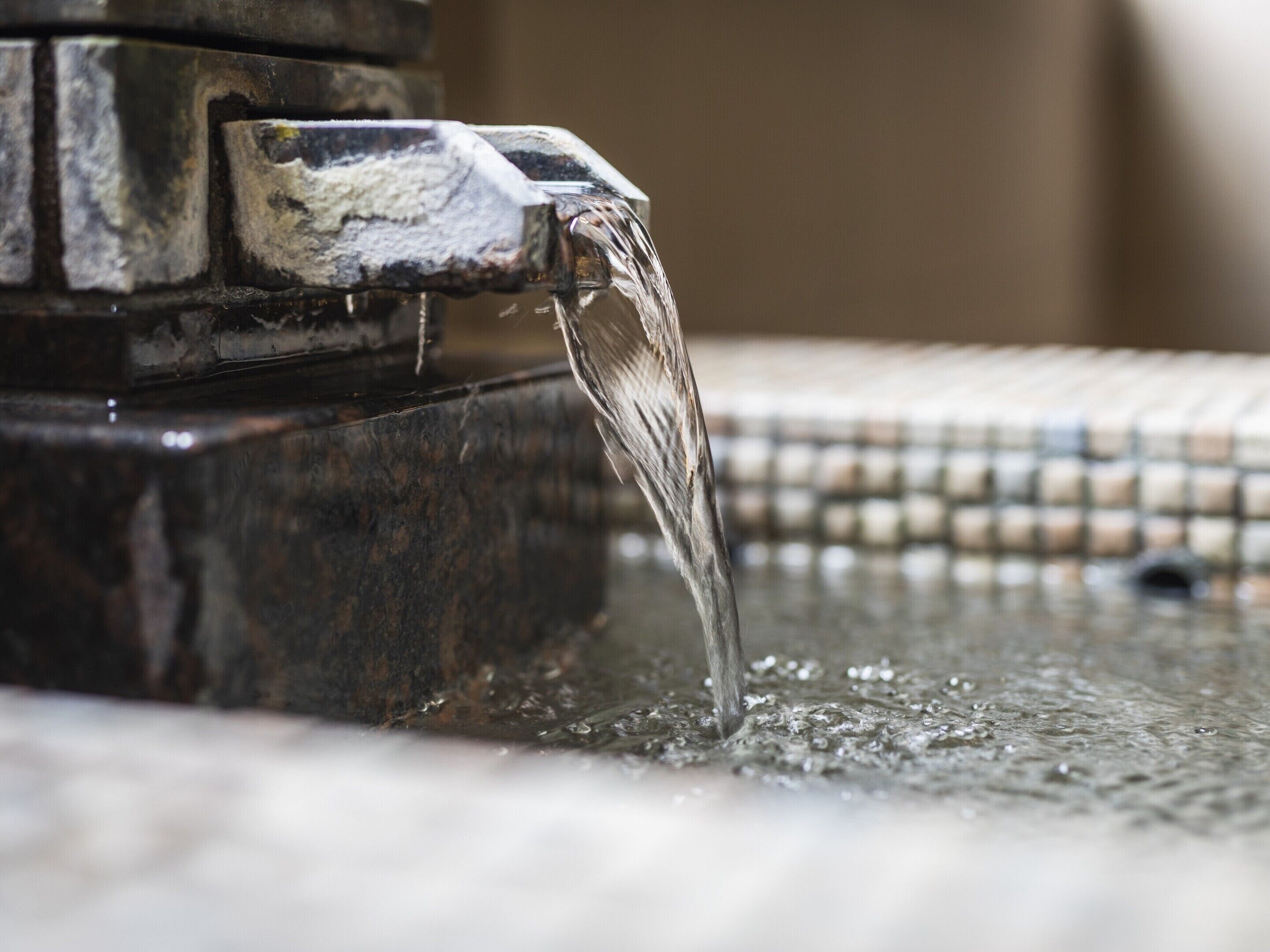 A close-up of water flowing from a faucet into a basin.