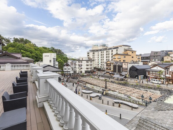 Un bâtiment traditionnel japonais doté d’une terrasse en bois et offrant une vue sur le paysage urbain.