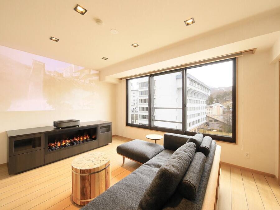 A modern living room with a large window, a fireplace, and a sofa.