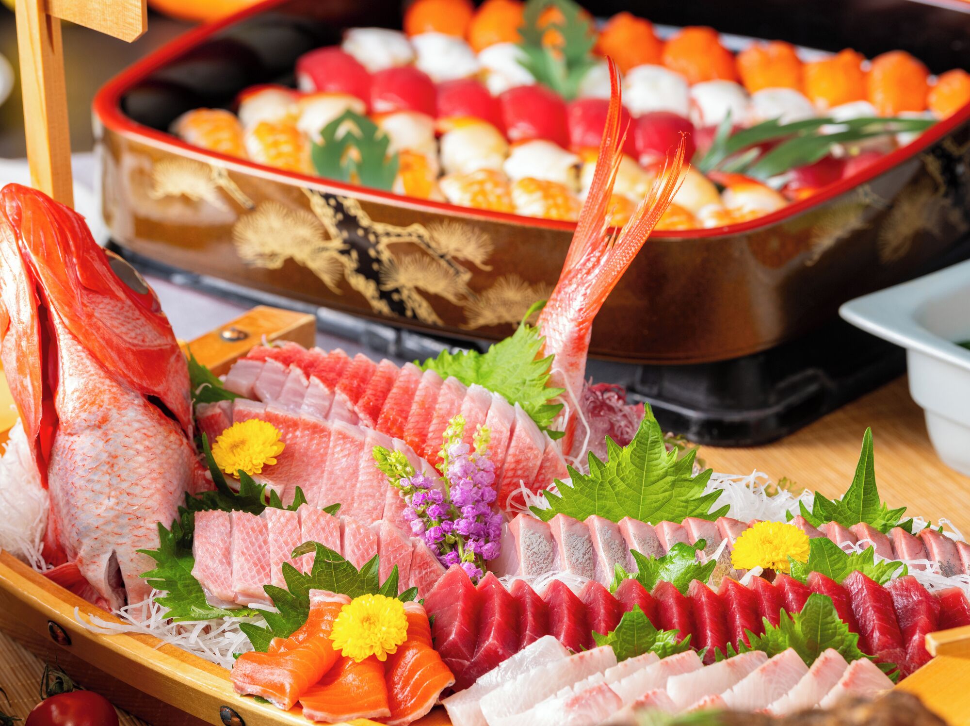 A variety of sushi and sashimi on a wooden tray.