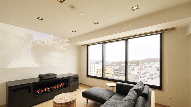 A modern living room with a large window, a fireplace, and a projector screen. - Hotel Ichii (Kusatsu)