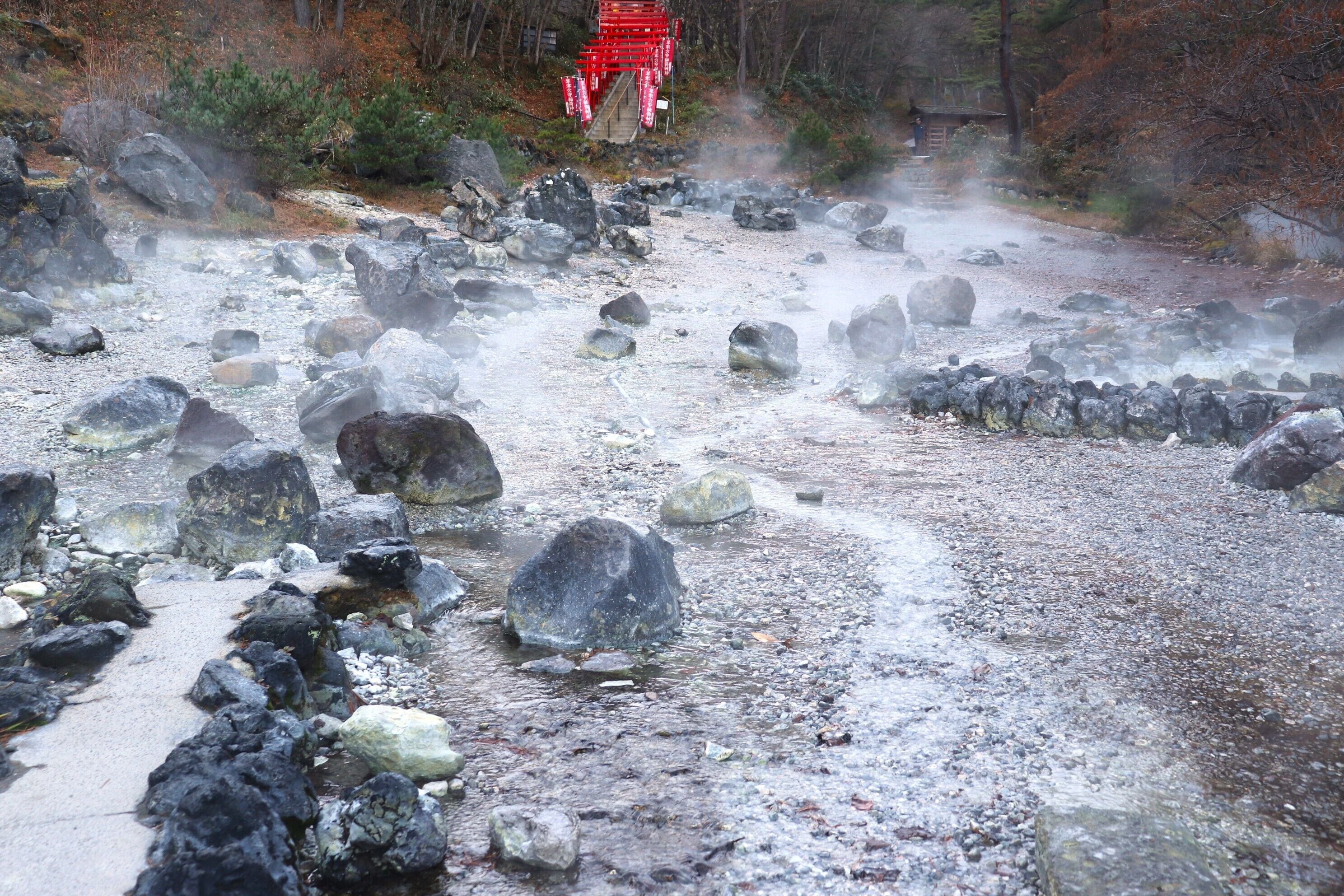 Un sendero pedregoso que lleva a una estructura roja en un entorno natural.