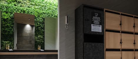 A modern bathroom with a green wall, a mirror, a towel rack, and a wooden cabinet.
