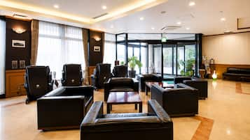 A hotel lobby with leather seating, a reception desk, and large windows.