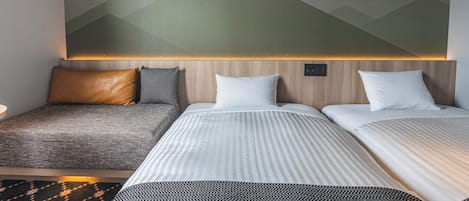 A hotel room with a bed, a sofa, and a wall-mounted light.
