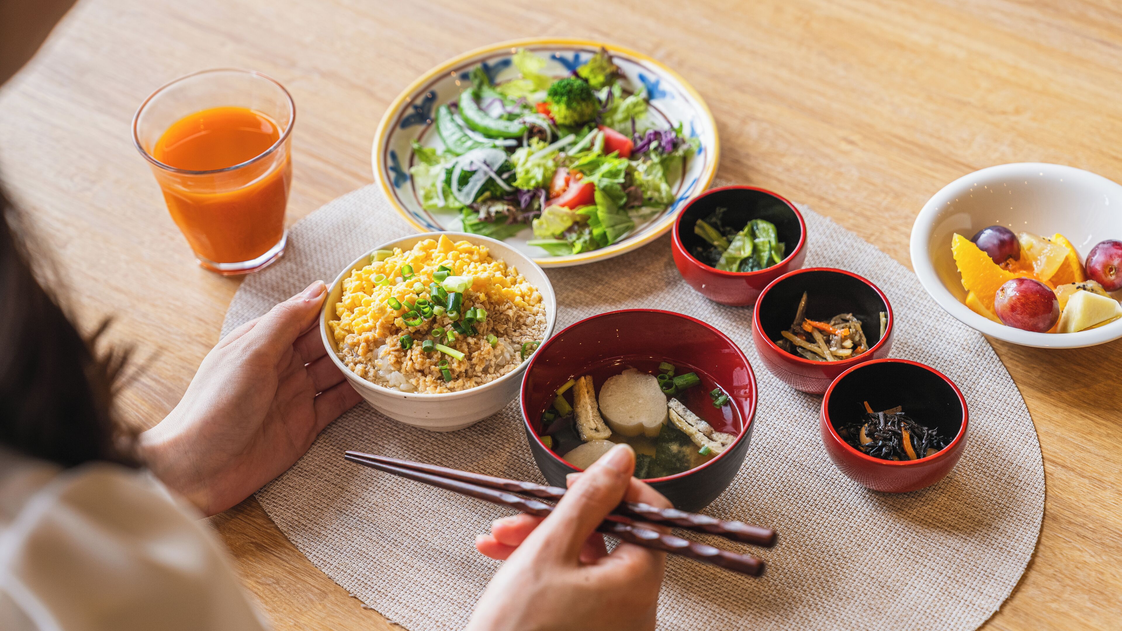 A dining table with various dishes, including a bowl of rice, a bowl of soup, and a plate of salad.