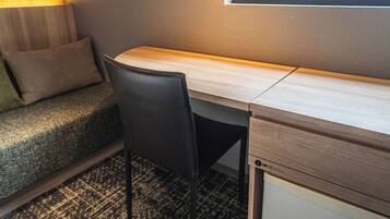 A compact hotel room with a bed, a desk, and a chair.