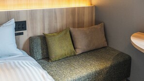A compact hotel room with a bed, a sofa, and a bedside table. - Tsukuba No Yu Urban Hotel (Tsukuba)