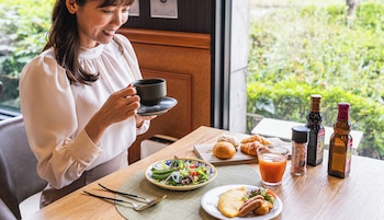 Una persona sentada a una mesa con comida, una taza y dos botellas.