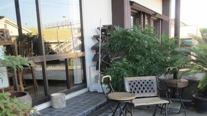 A patio with outdoor seating, potted plants, and a building entrance. - Tsukuba Town Hotel (Joso)