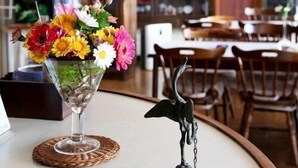 A dining area with a table set for two, a vase of flowers, and a decorative bird sculpture. - Tsukuba Town Hotel (Joso)