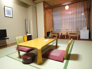 Una habitació japonesa tradicional amb tatami, una taula de fusta baixa i un televisor.