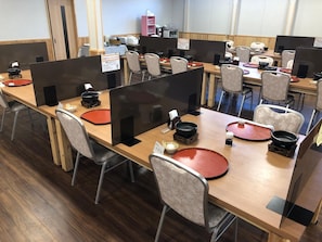 A conference room with multiple tables, chairs, and partition screens. - Hotel Harumoto (Nikko)