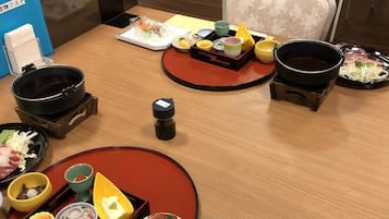Una comida tradicional japonesa con varios platos y utensilios sobre una mesa de madera.