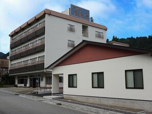 A multi-story building with a flat roof and a sign above the entrance. - Hotel Harumoto (Nikko)