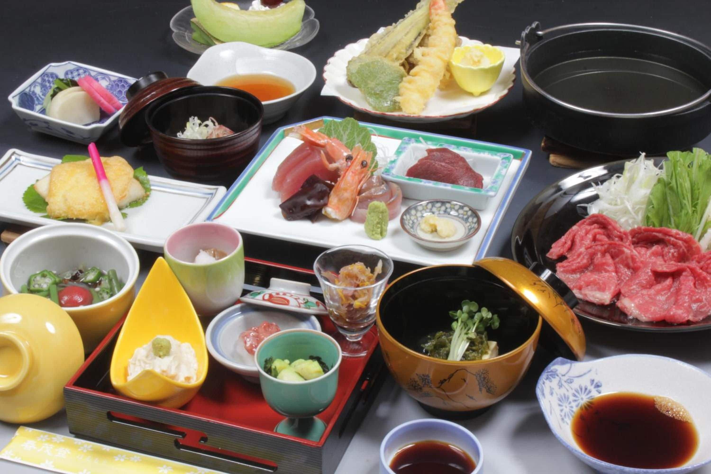 A variety of Japanese dishes including sushi, sashimi, and tempura, served on a table with multiple small bowls and plates.