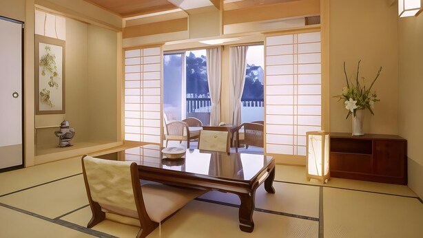 A traditional Japanese room with tatami flooring, a low wooden table, and a view of a balcony. - Hotel Spax Kusatsu (Kusatsu)
