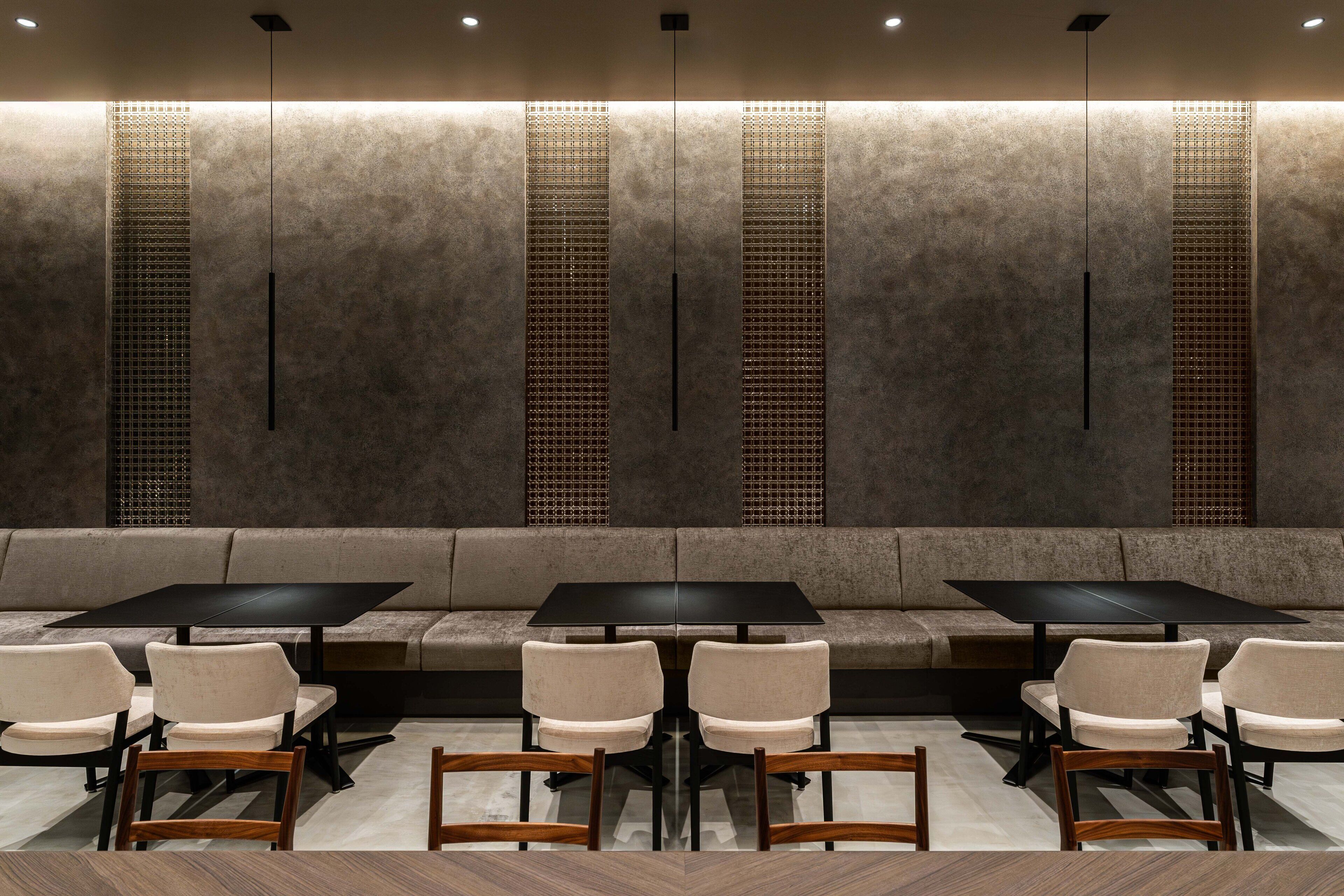 A modern interior with a seating area, tables, and a patterned wall.