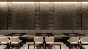 A modern interior with a seating area, tables, and a patterned wall.