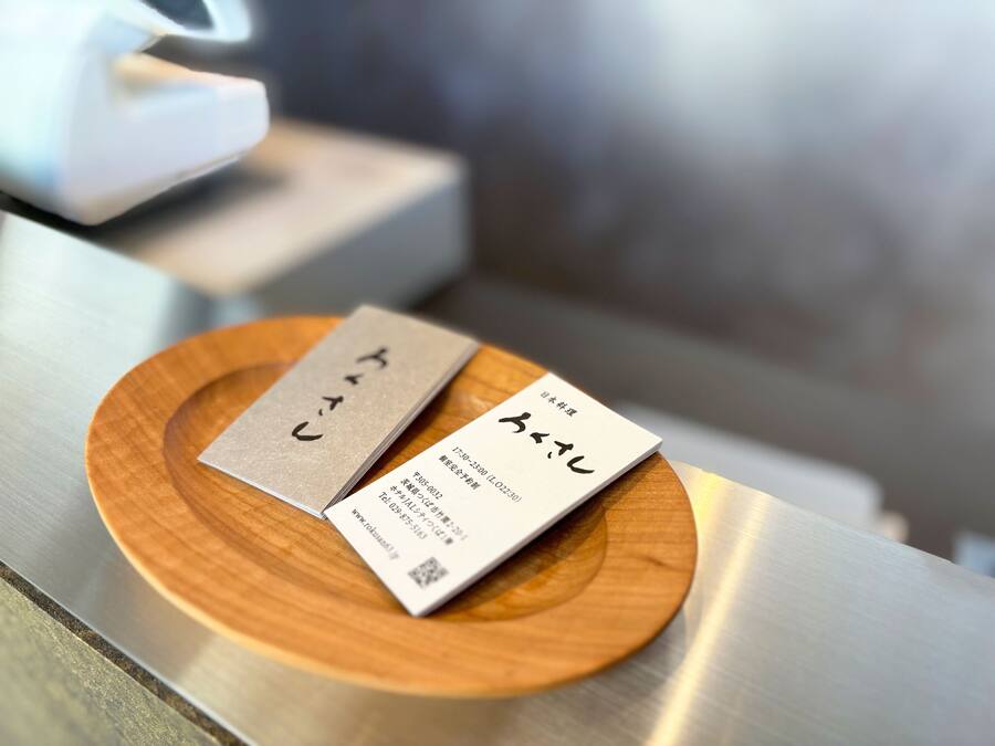Two business cards on a wooden coaster.