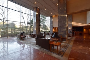 Un hall d’entrée spacieux, doté de grandes fenêtres, d’un comptoir de réception et de plusieurs espaces où s’asseoir.