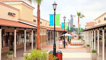Un centro comercial con paseos techados, palmeras y una estatua a lo lejos.