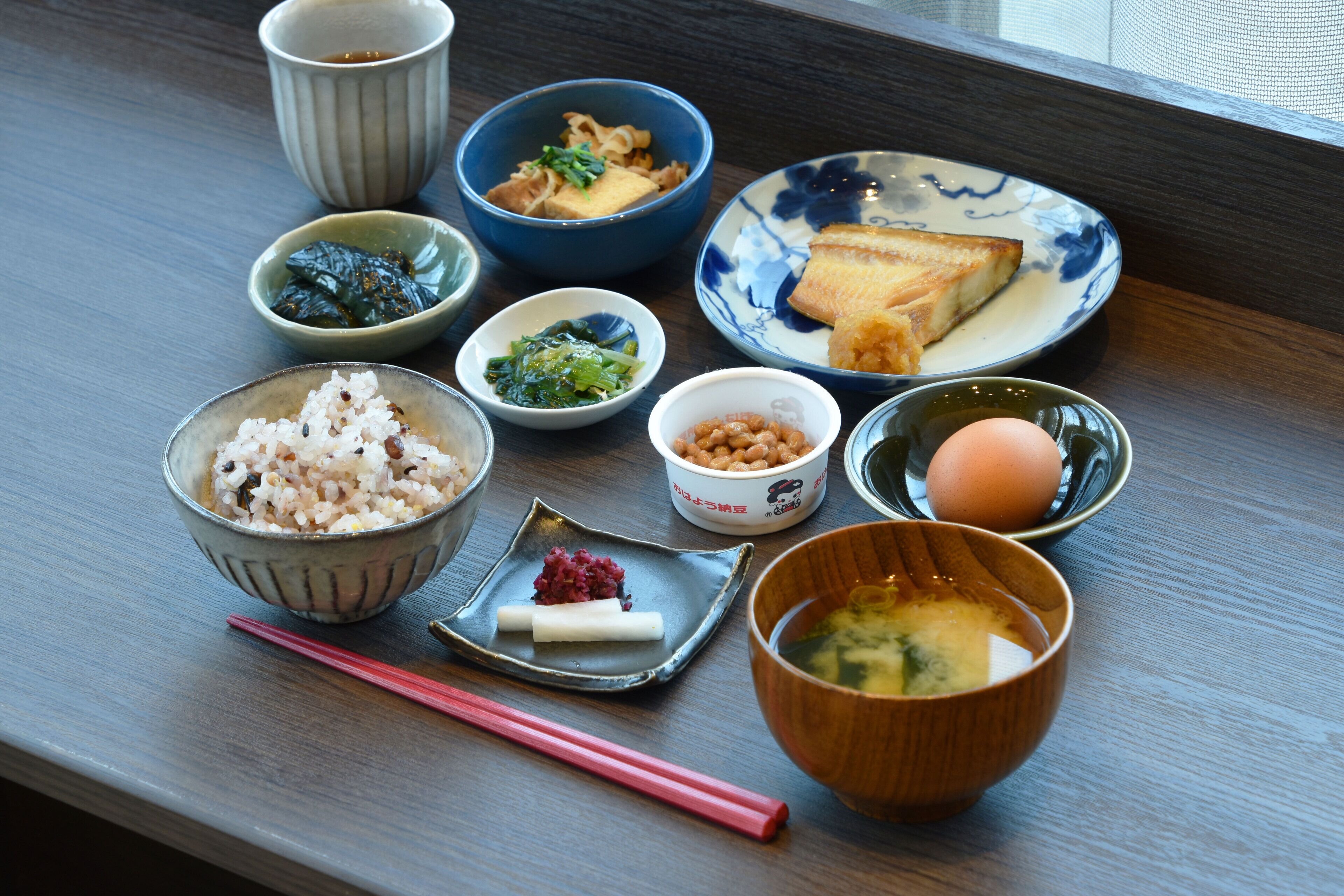 A variety of dishes on a tray, including rice, soup, and a plate with slices of fish.