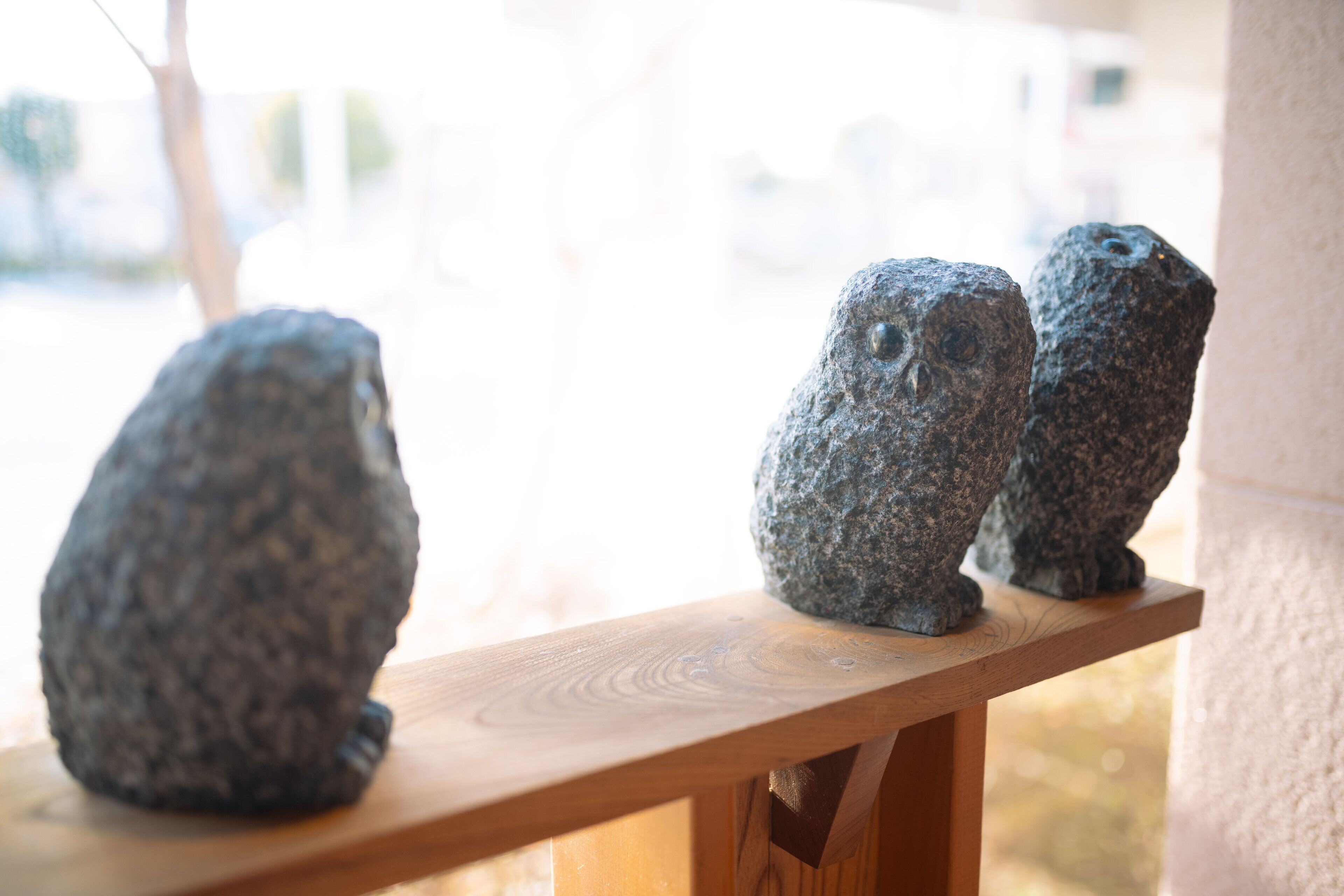 Three stone sculptures on a wooden ledge.