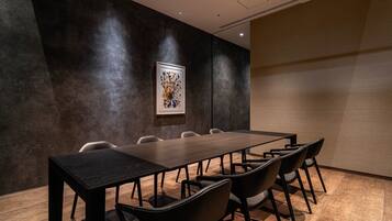 A conference room with a long table, six chairs, and a framed artwork on the wall.