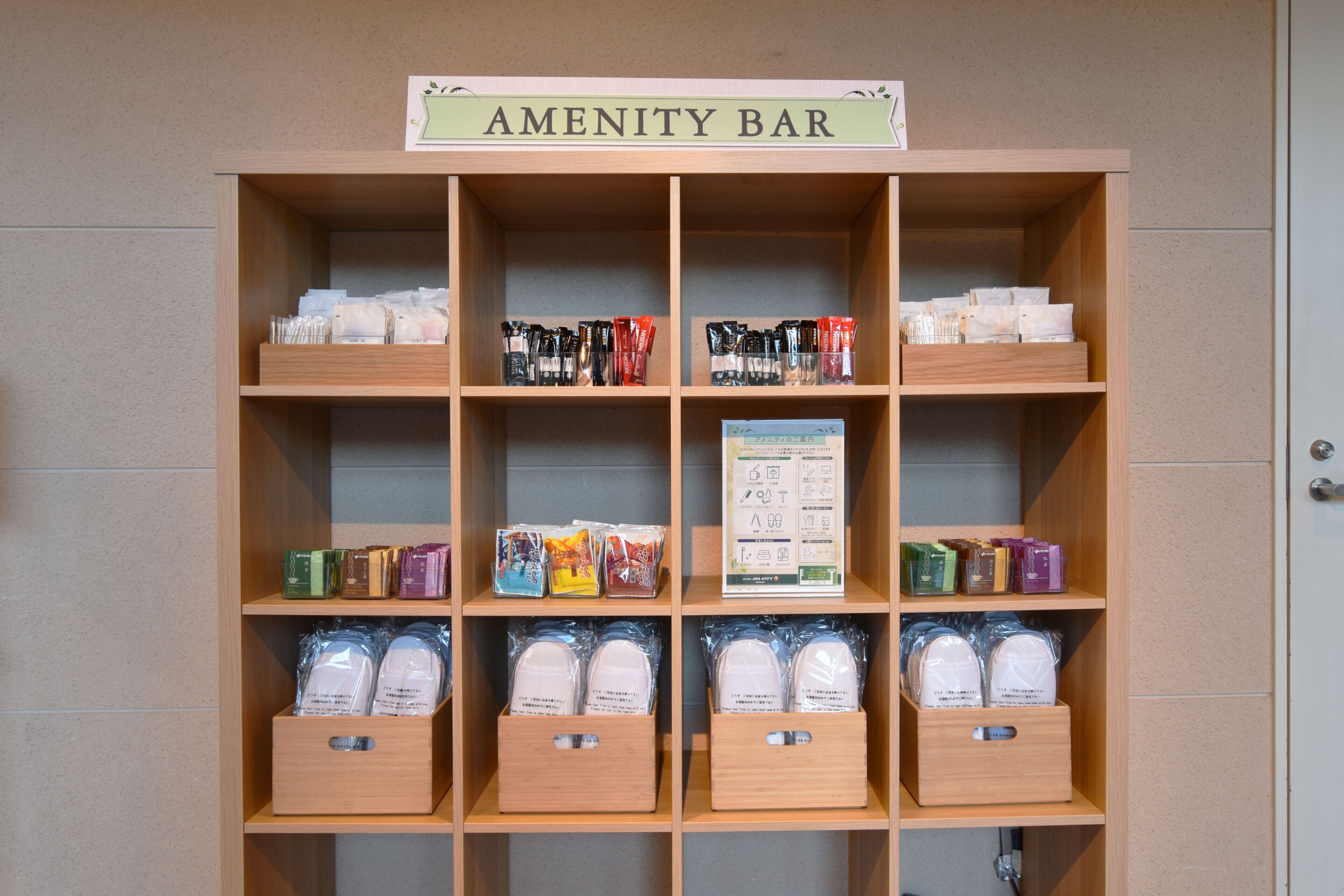 A wooden shelf labeled "AMENITY BAR" with various packaged items and a sign with icons.
