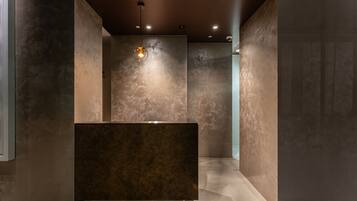 A modern bathroom with a central sink, recessed lighting, and textured walls.