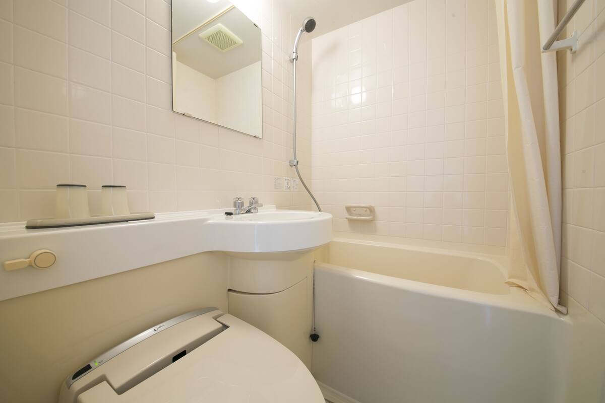 A bathroom with a white sink, mirror, and bathtub.