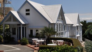 A white building with a gabled roof and a covered outdoor seating area with tables and chairs. - Country Inn The White Marine (Tonosho)