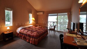 A hotel room with a large bed, a desk with a computer, a chair, and a view of the outdoors through large windows. - Country Inn The White Marine (Tonosho)