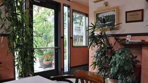 A restaurant interior with a table, chairs, potted plants, and a view of the outside. - Country Inn The White Marine (Tonosho)