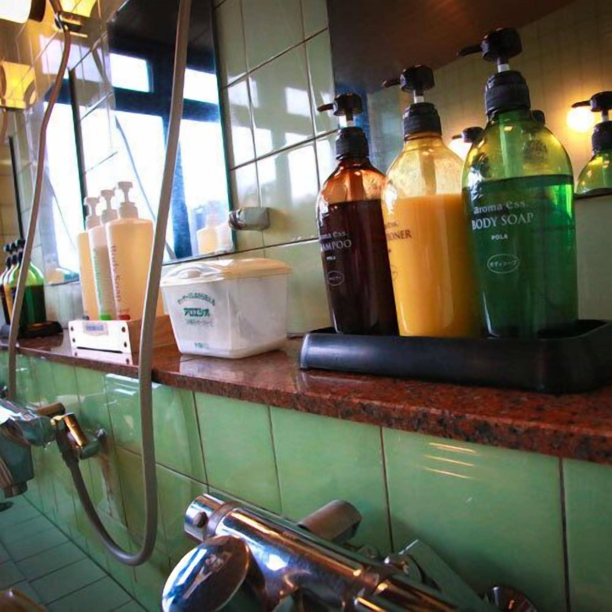 A bathroom with various toiletries on a counter, including bottles of body soap and shampoo.