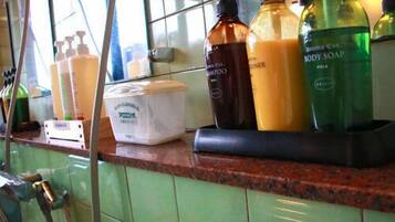 A bathroom with various toiletries on a counter, including bottles of body soap and shampoo.