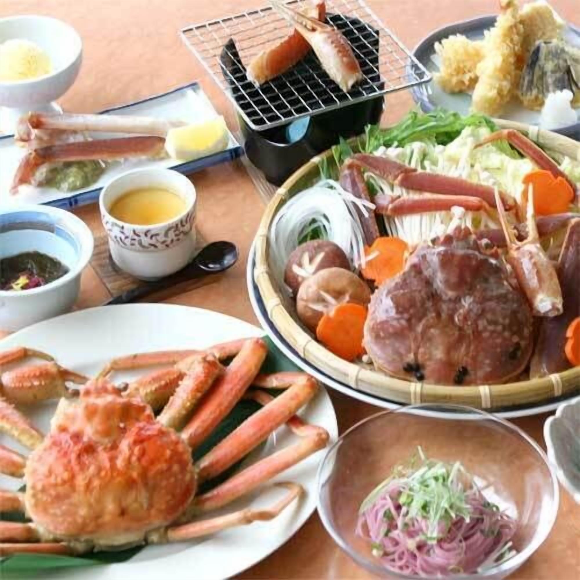 Ett urval av rätter med skaldjur, inklusive krabbben, fisk och grönsaker, serverade på ett träbord.
